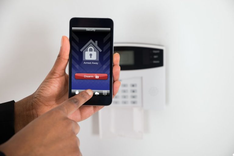A person checking a security system on an iPhone, focused on the screen in a well-lit room.