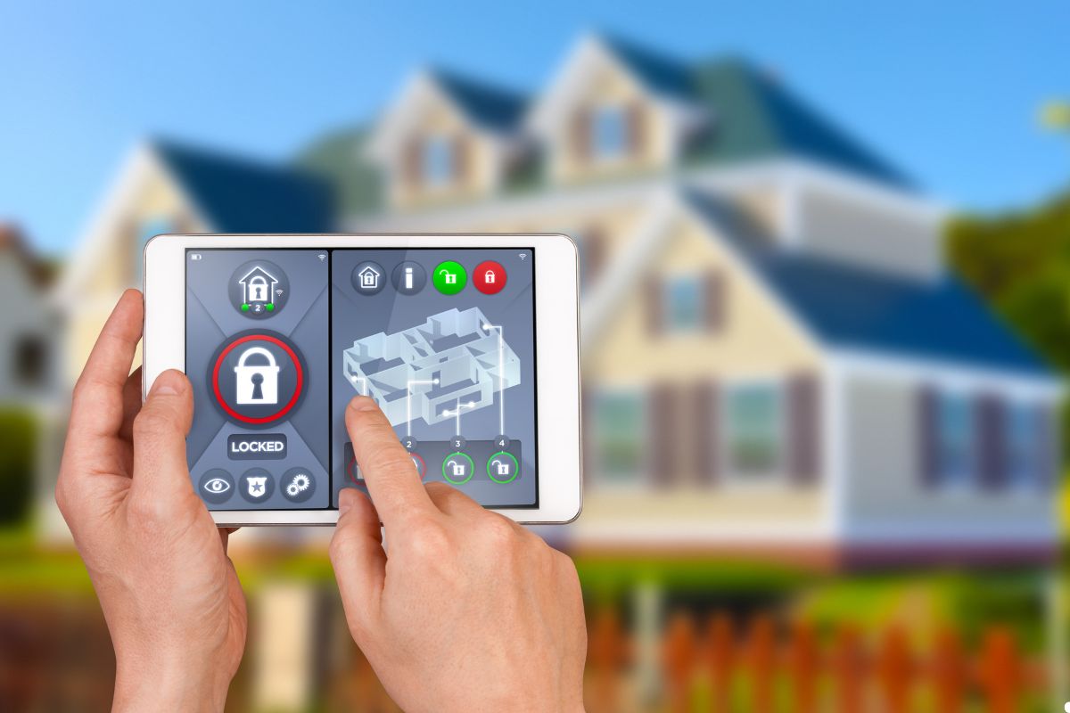 A tablet showing a home security interface, held by hands, with a secure home depicted in the background. 