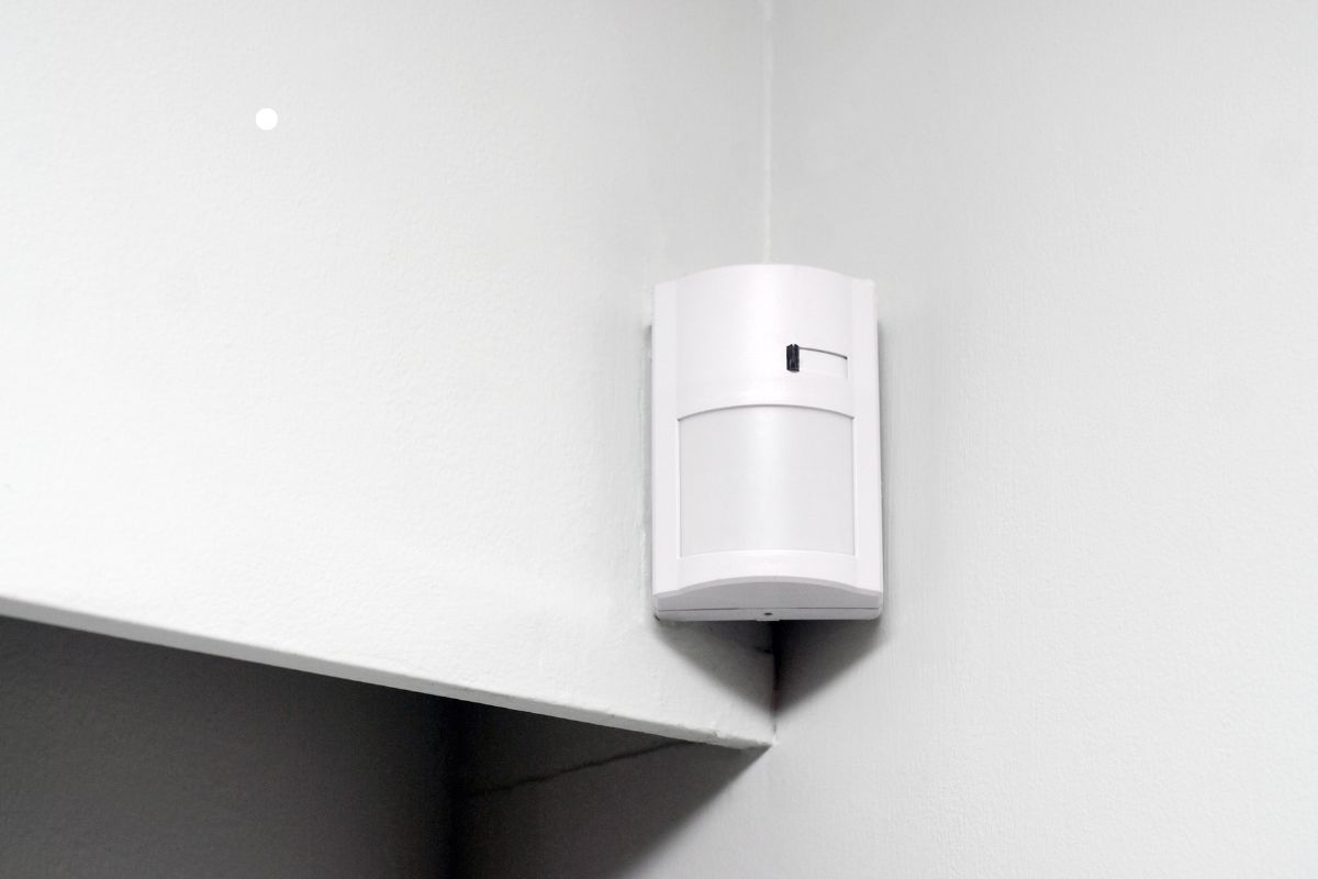 A white alarm with motion sensors, mounted on a wall, designed for security and surveillance.