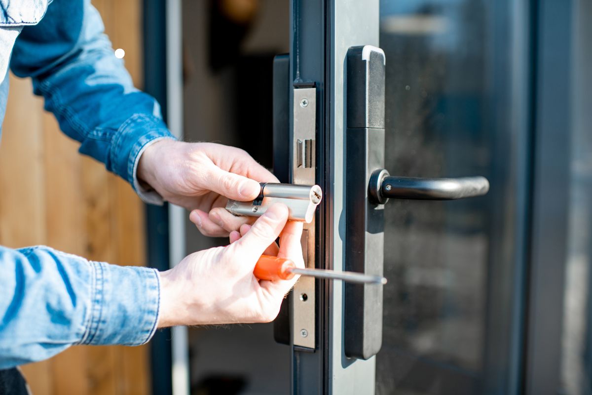 A man uses a screwdriver to fix a door handle, reinforcing the door's strength and functionality.